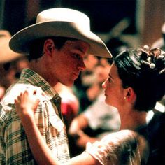 a man and woman dance together in front of a large group of people wearing cowboy hats