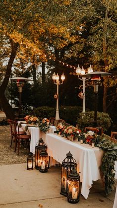 a long table with lanterns and flowers on it is set up for an outdoor dinner