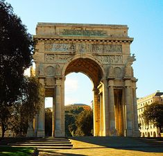 an arch in the middle of a park with steps leading up to it and trees on either side