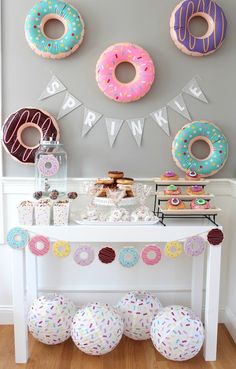 a table topped with lots of donuts covered in frosting and sprinkles