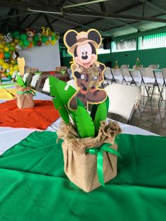 a mickey mouse centerpiece sitting on top of a green table cloth covered tablecloth