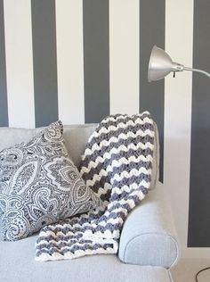 a couch with two pillows and a blanket on it in front of a striped wall