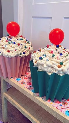 two cupcakes with white frosting and red balloons