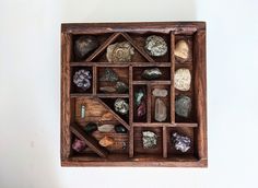 a wooden box filled with rocks and stones on top of a white wall next to a window