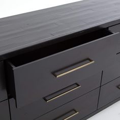 a black dresser with gold handles and drawers on it's sides, against a white background