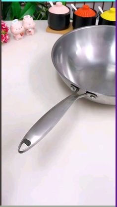 a silver pan with a handle sitting on top of a counter next to other kitchen utensils