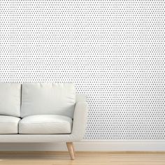 a white couch sitting in front of a wall with black and white dots on it