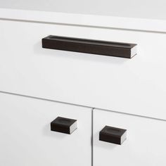 a white cabinet with black handles and knobs