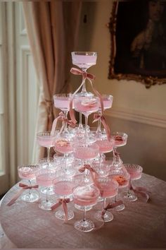 a table topped with lots of wine glasses filled with pink liquid on top of it