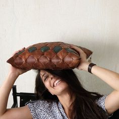 a woman sitting in a chair holding a pillow over her head and smiling at the camera