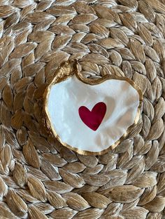 a piece of wood with a heart painted on it's side sitting on a woven surface