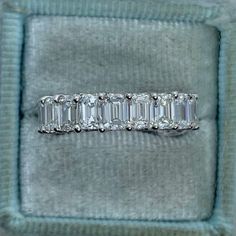 an emerald cut diamond ring sits in a velvet box