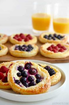 small desserts with berries and blueberries are on a plate next to other pastries