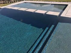 an empty swimming pool surrounded by grass and trees