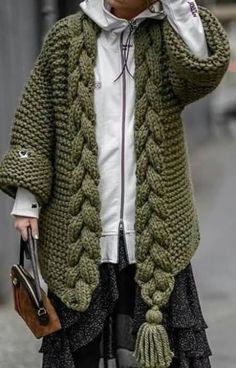 a woman walking down the street while talking on her cell phone and wearing a green knitted cardigan