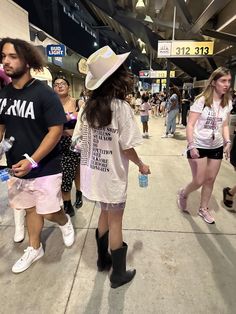 a man and woman walking down a sidewalk in the middle of an airport with other people