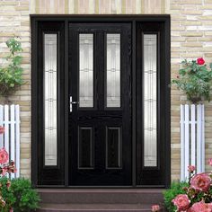 a black front door with glass panels and pink flowers in the foreground on a brick wall