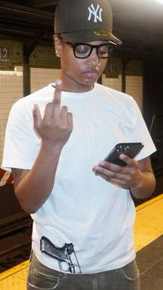 a young man in a new york yankees hat is using his cell phone at the subway station