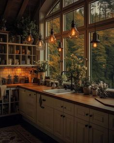 a kitchen filled with lots of windows next to a sink and counter top under hanging lights