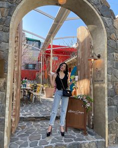 a woman standing in front of a stone archway