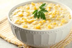 a white bowl filled with corn on top of a checkered table cloth next to a napkin