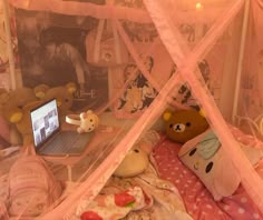 a laptop computer sitting on top of a bed covered in pink netted sheets and teddy bears