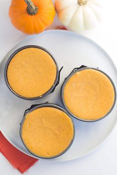 three pumpkin pies sitting on top of a white plate next to an orange pumpkin