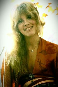 a woman with long blonde hair smiling at the camera