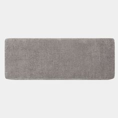 a gray bath mat is shown on a white background, it has a long edge