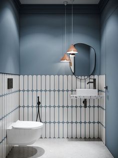 a white toilet sitting next to a sink in a bathroom under a mirror and lights