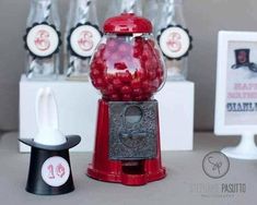 a red gummy machine sitting on top of a table next to a black and white object