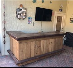 a wooden bar with a flat screen tv mounted on the wall behind it in front of a door