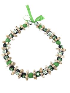 a green and white beaded bracelet with shells on it's side, tied in a bow