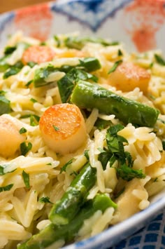 a bowl filled with pasta and vegetables on top of a blue and white table cloth