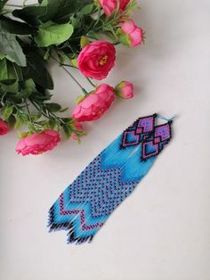 a blue beaded bracelet next to pink roses