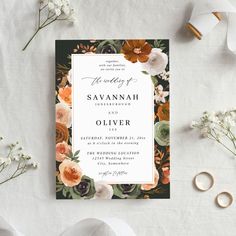 an elegant wedding card with flowers and greenery