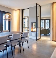 a dining room table and chairs in front of large windows