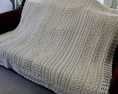 a white knitted blanket sitting on top of a couch