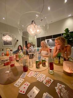 people are sitting around a table with cards and wine glasses on it while playing cards