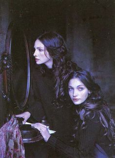 two women sitting next to each other in front of a mirror