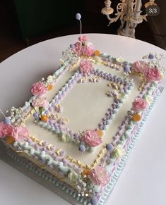 a square cake decorated with flowers and beads on a table next to a candle holder