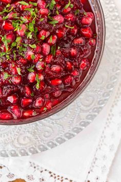 a glass bowl filled with cranberry sauce on top of a white doily