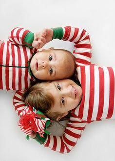 two young children laying on top of each other wearing matching red and white striped pajamas