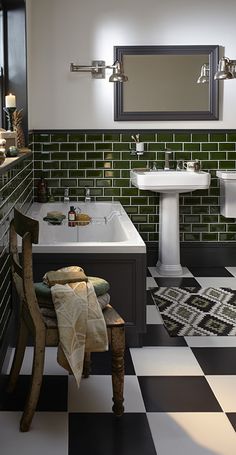 a black and white checkered floor bathroom with green tiles on the walls, sink, toilet and mirror