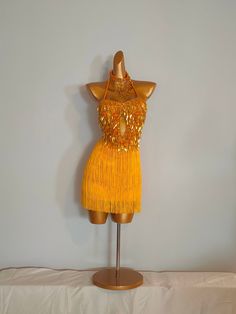 a mannequin wearing a yellow dress with gold sequins on it's chest