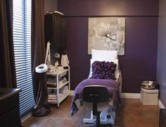 a bedroom with purple walls and white bedding in the corner, along with a chair