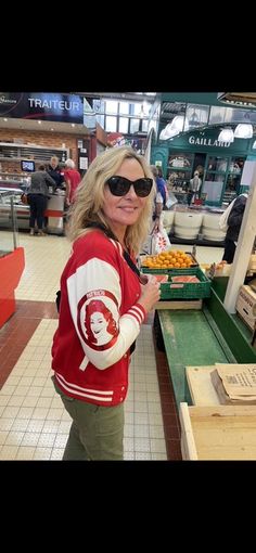 a woman standing in front of a table filled with oranges