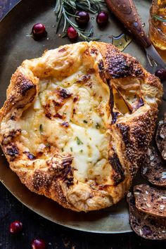 baked bread with cheese and herbs on a plate next to some other food items, along with a glass of wine