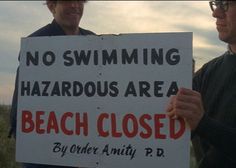 a sign that says no swimming hazardous area beach closed