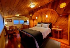 a bedroom with wood paneling and a bed in the corner, along with two chairs